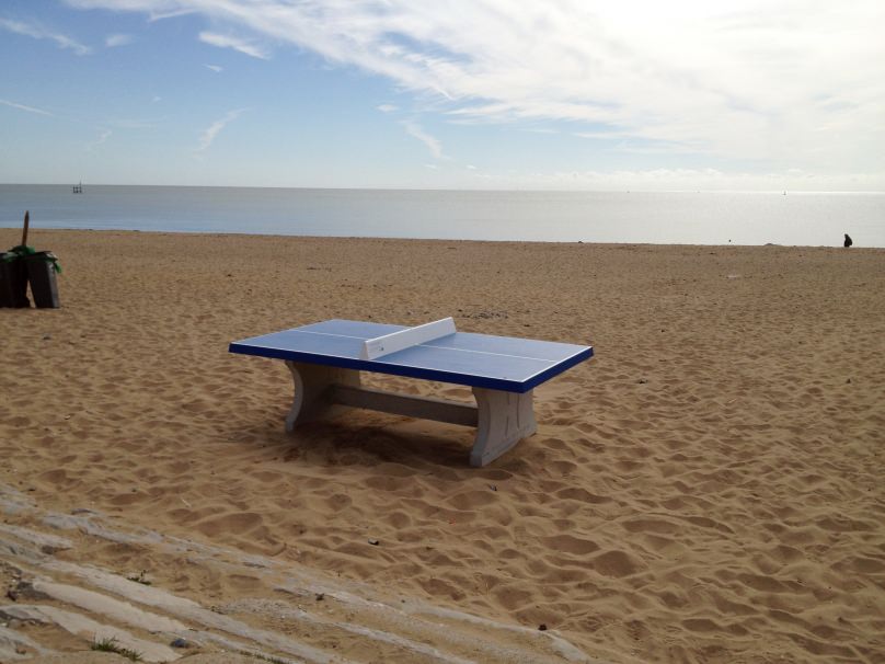 Blauwe betonnen tafeltennistafel op het strand